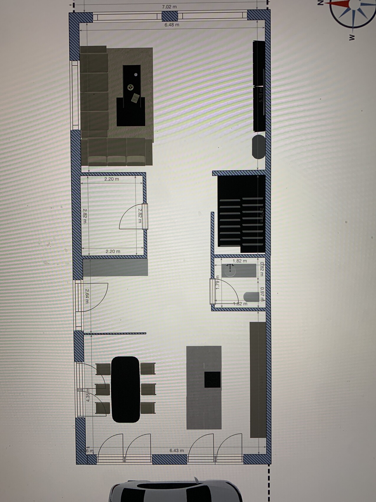 Grundriss eines Hauses: Wohnzimmer mit Sofa, Esstisch, Küche mit Insel, Bad, Treppe.