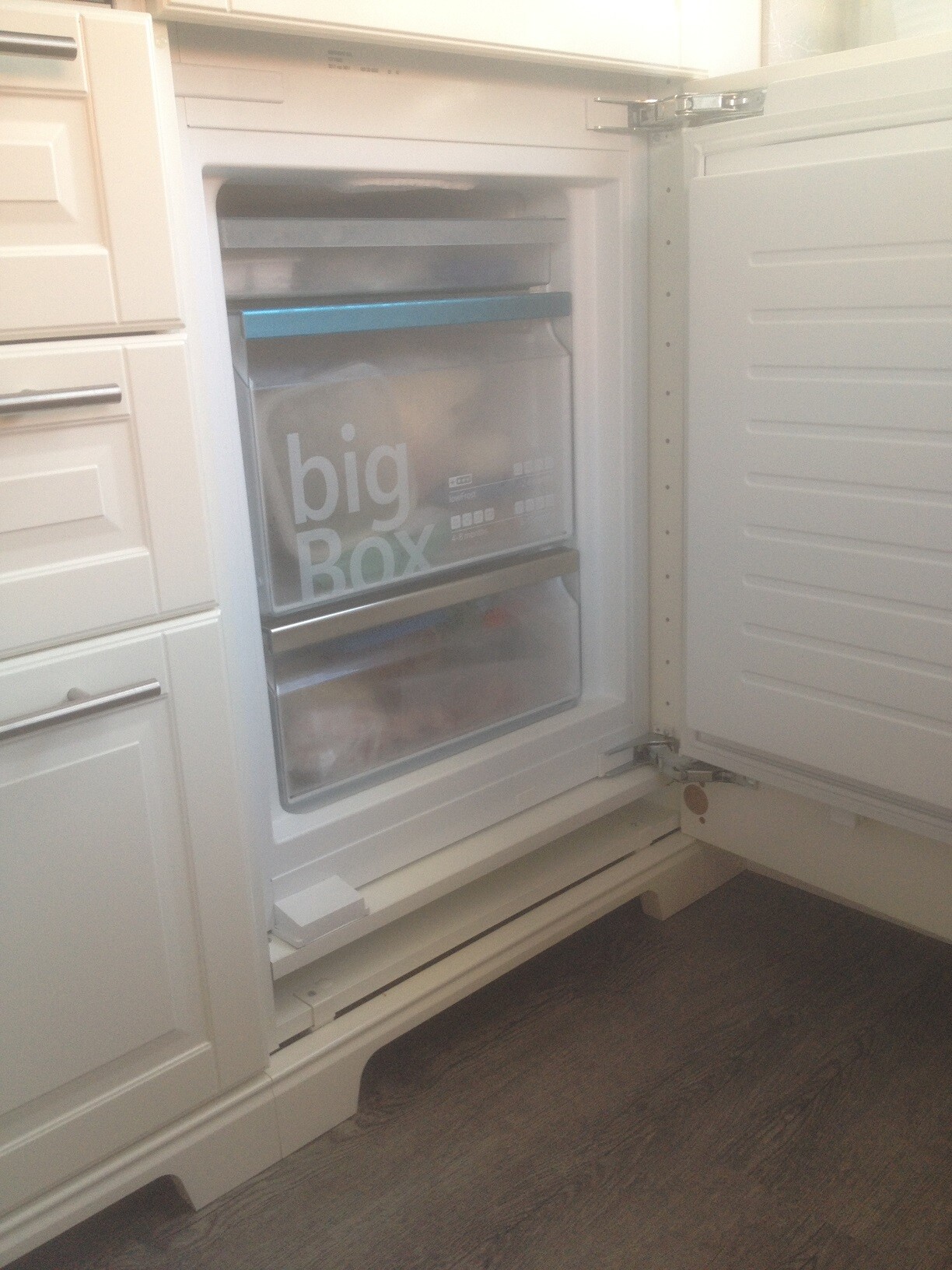 Offene Gefriertruhe in weißer Küche, Tür mit transparentem Frontpanel und 'big Box' Aufschrift.