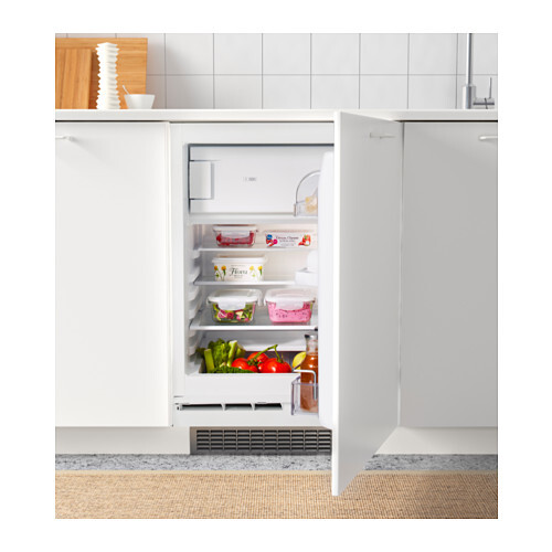 Kompakter Einbaukühlschrank mit offener Tür in der Küche; oben Joghurt, unten frisches Gemüse.