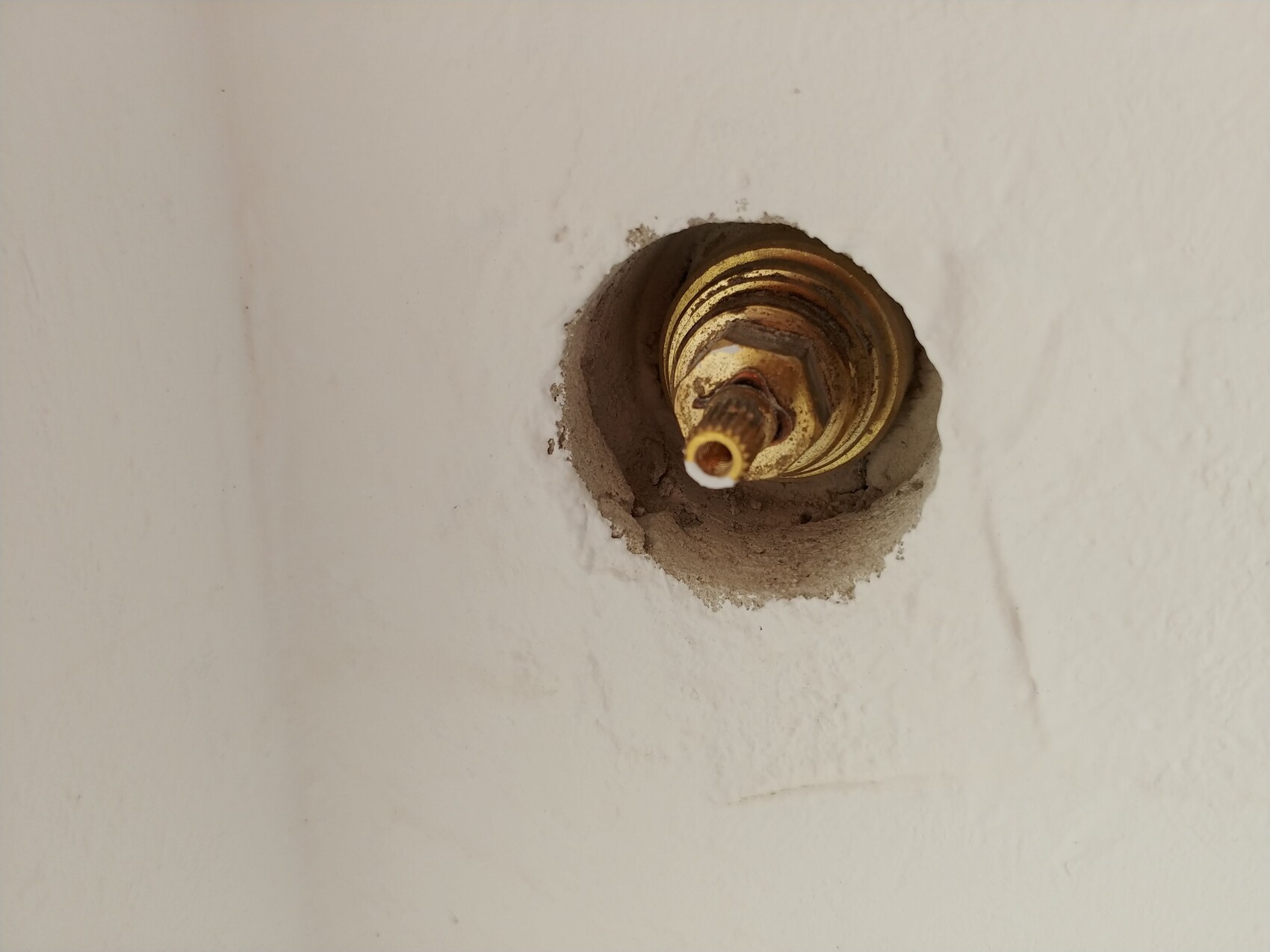 Nahaufnahme einer goldfarbenen Lampenfassung in einer Wand mit Mörtel umgeben