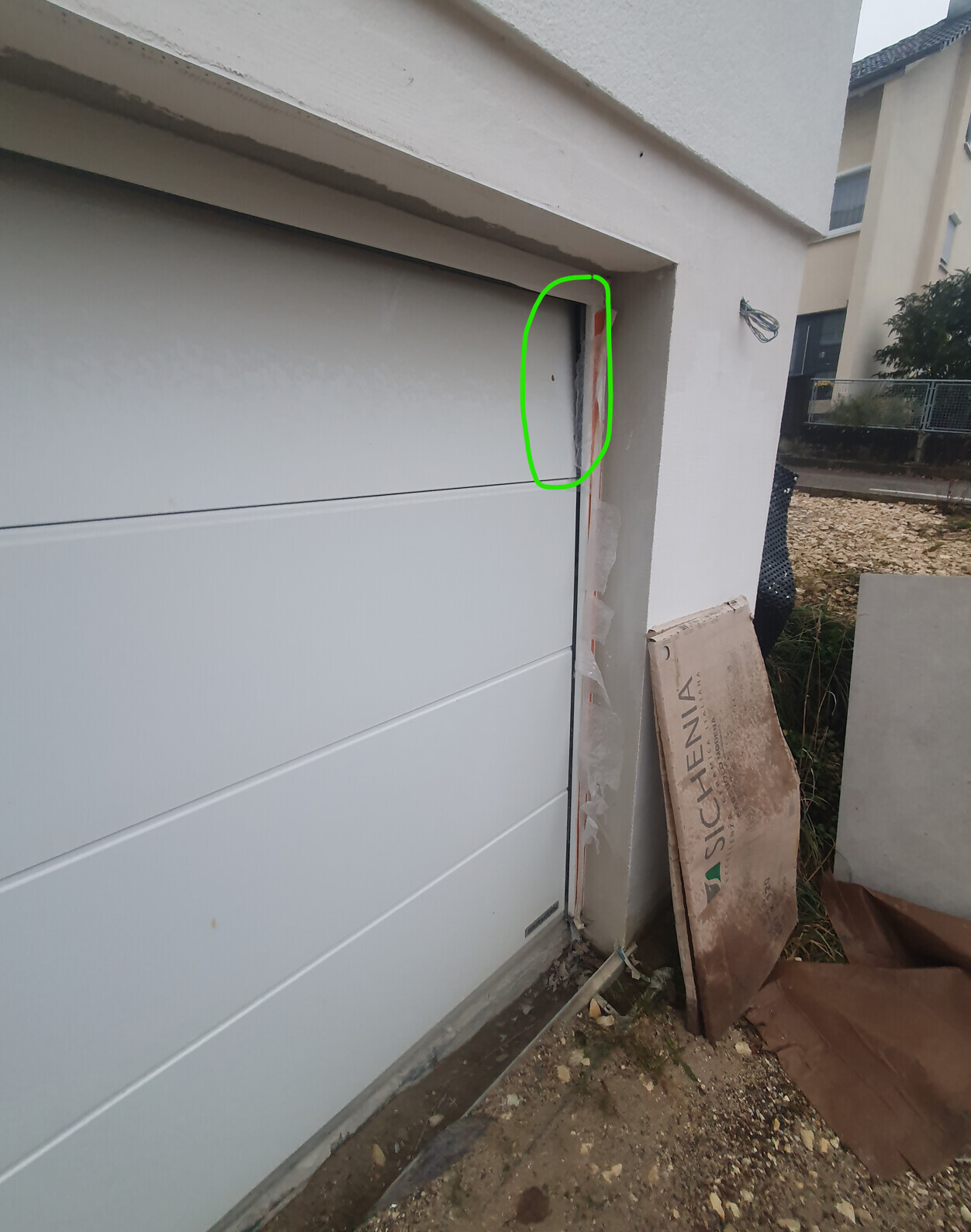 Spalt zwischen Garagentür und Wand mit orangefarbenem Dichtungsband sichtbar.