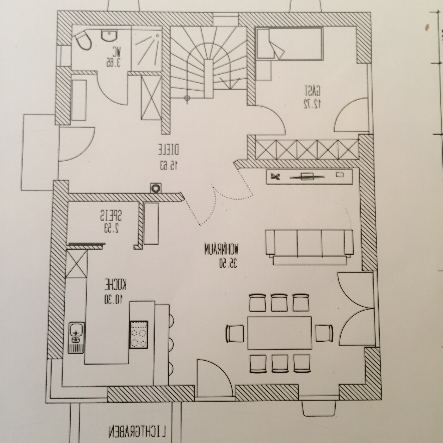 Grundrissplan eines Hauses mit offener Wohnküche, Essbereich, Eingang und Treppe