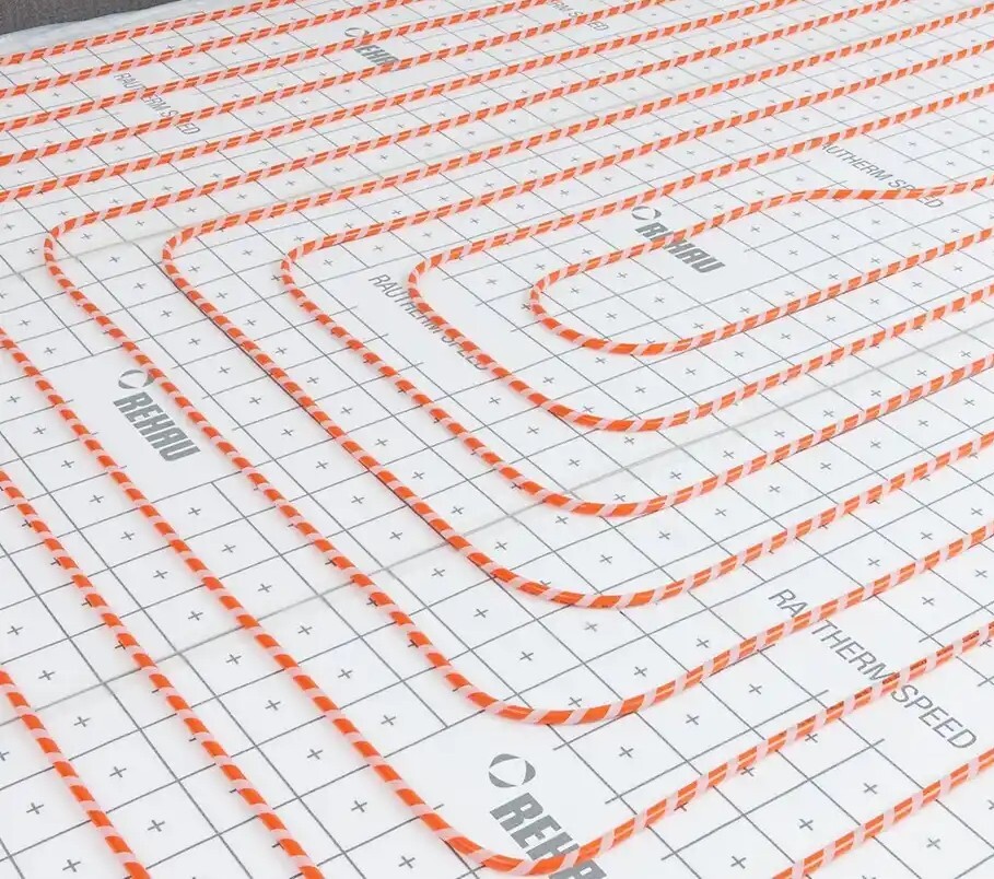 Orange Heizkabel-Schlaufen liegen geordnet auf einer Dämmunterlage für Fußbodenheizung.