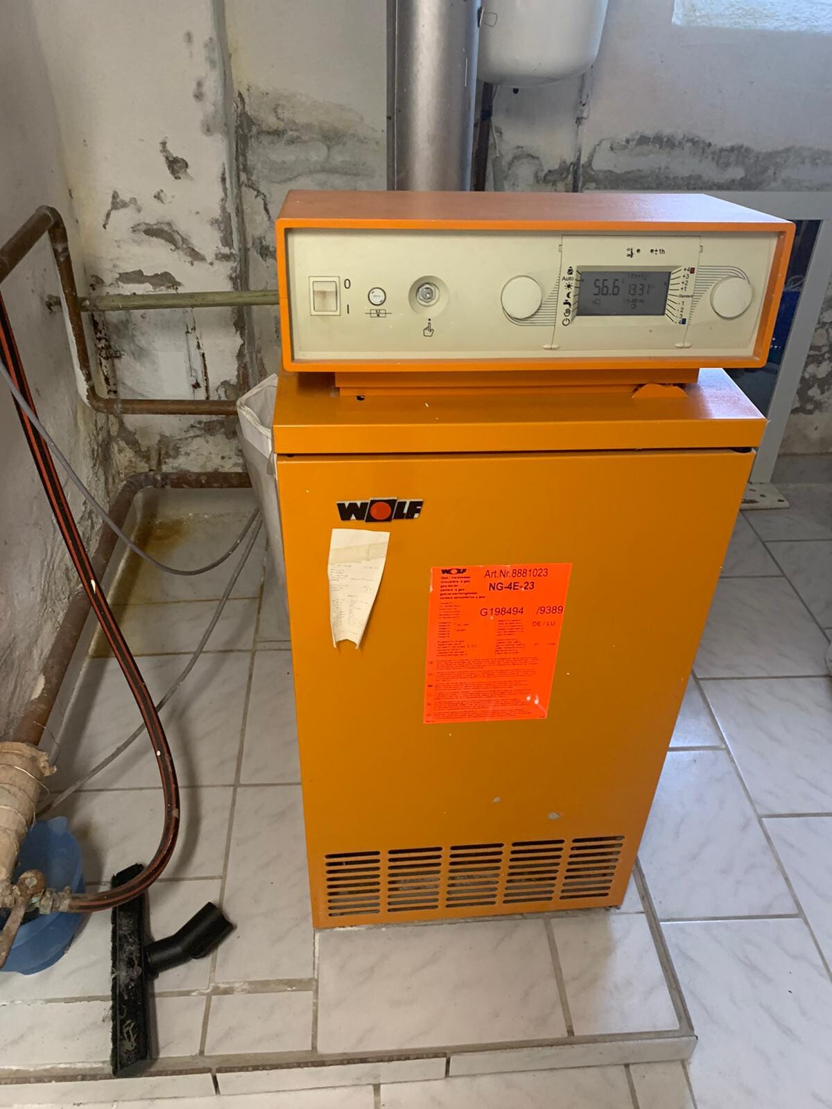 Orangefarbener Wolf-Heizkessel mit Display und Bedienelementen im Kelleraum.