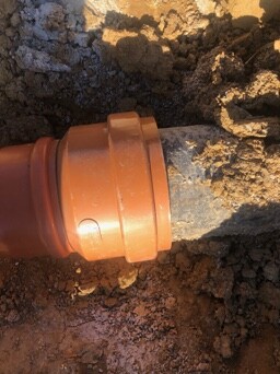 Orange PVC-Rohrverbindung im Boden, Erde drumherum