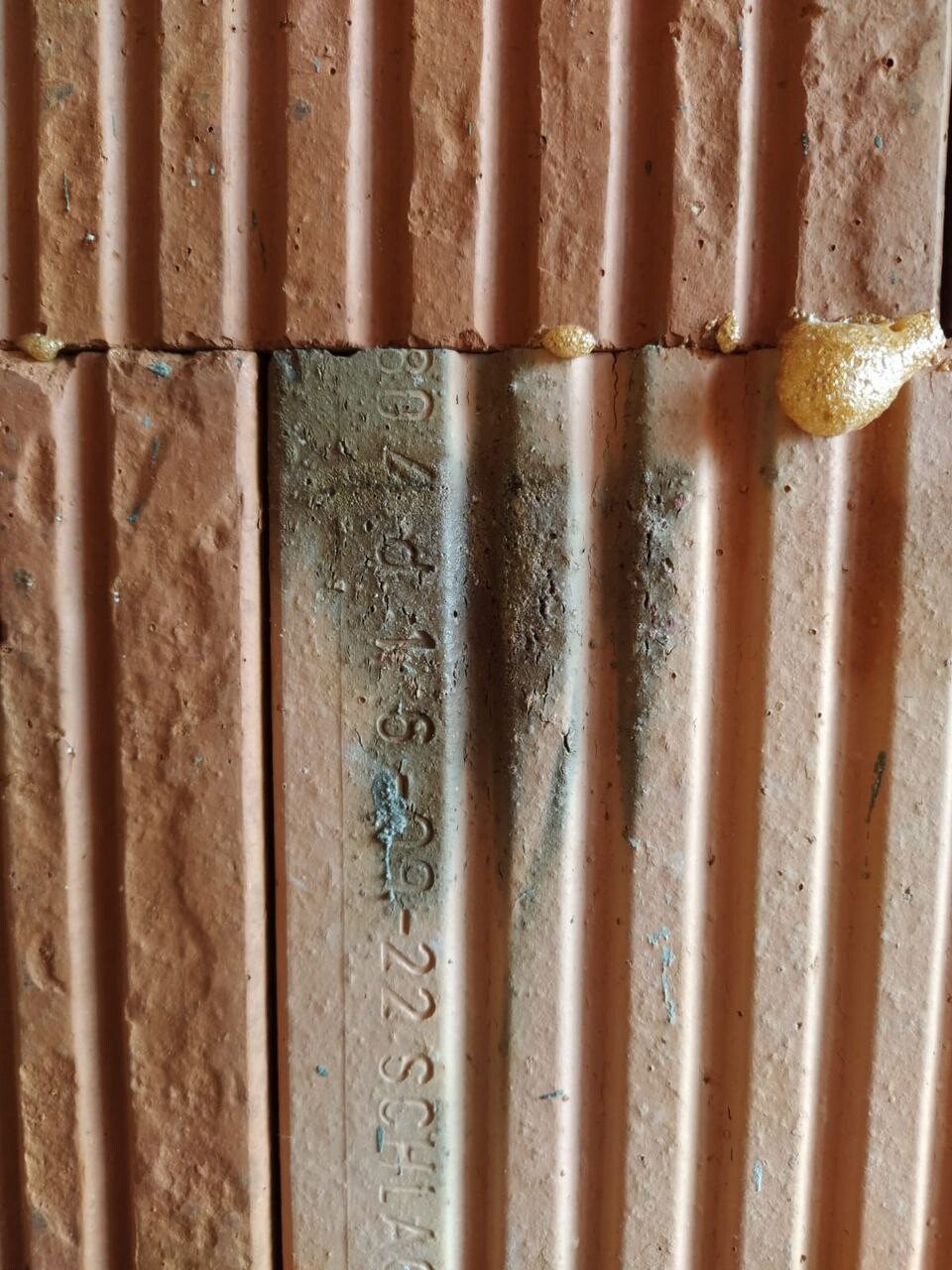 Rostorangefarbene, vertikale Rippenplatten; mittig grauer Streifen mit Zahlenstempel.