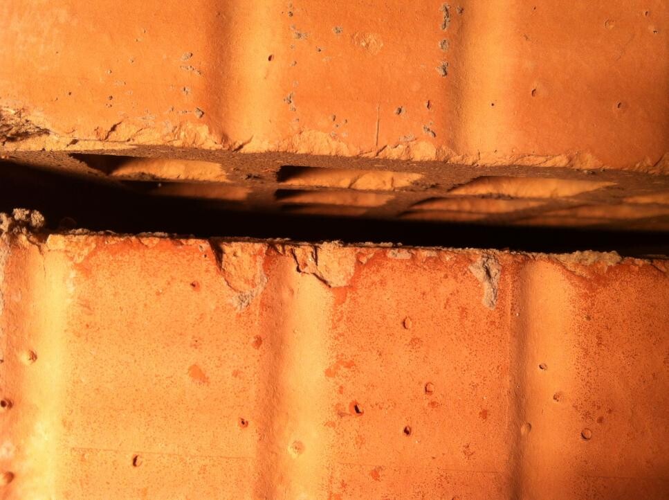 Nahaufnahme orangefarbener Dachziegel mit sichtbaren Unebenheiten und Spalten
