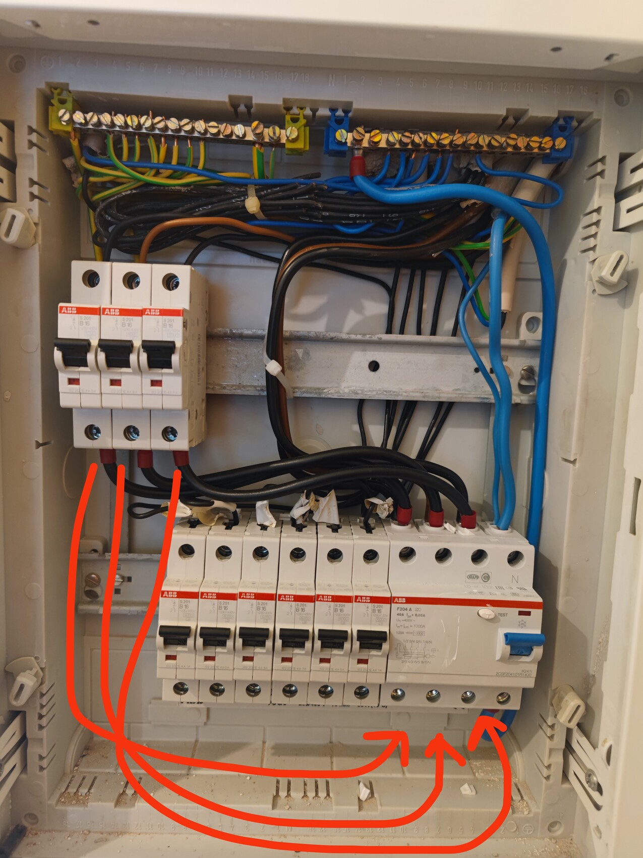 Elektrischer Schaltschrank mit Sicherungsautomaten und Kabeln; rote Pfeile markieren Verbindungen.