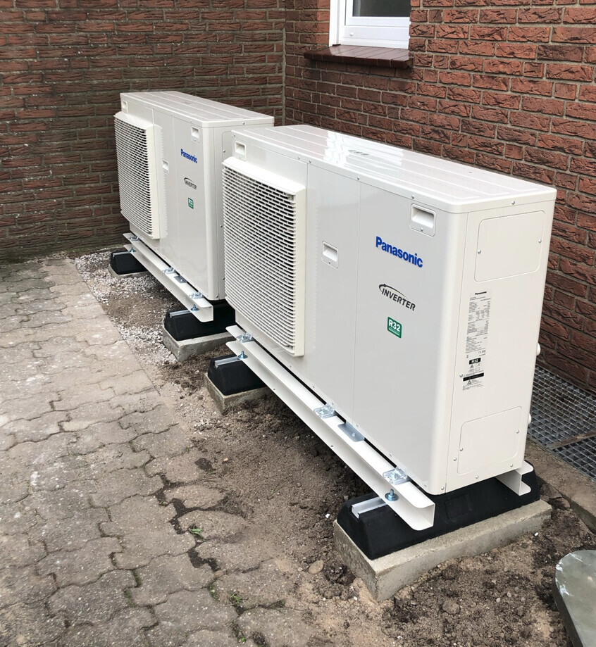 Zwei Panasonic-Inverter-Außenklimageräte vor Ziegelwand auf Fundamenten montiert