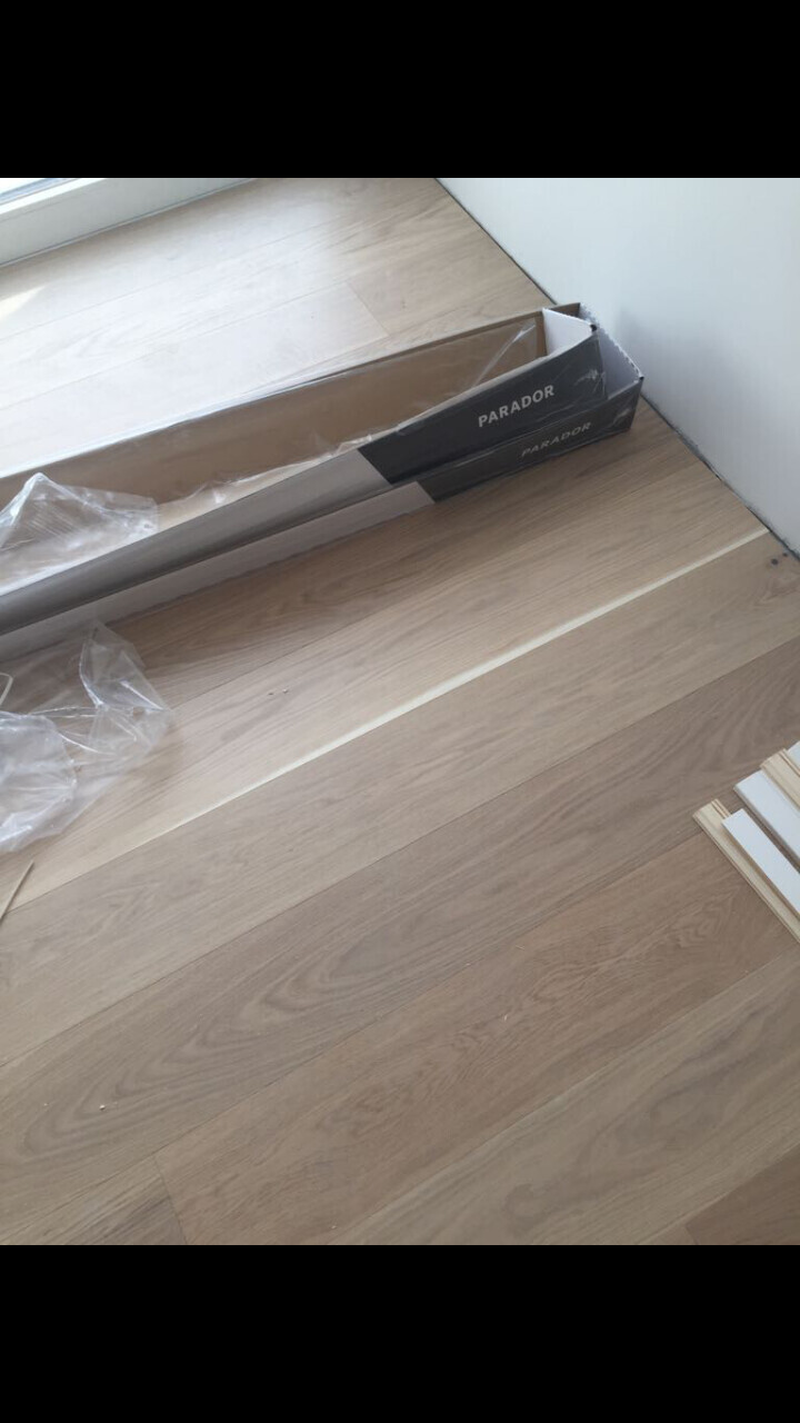 Holzoptik-Laminatboden mit Parador-Verpackung am Rand eines hellen Raums
