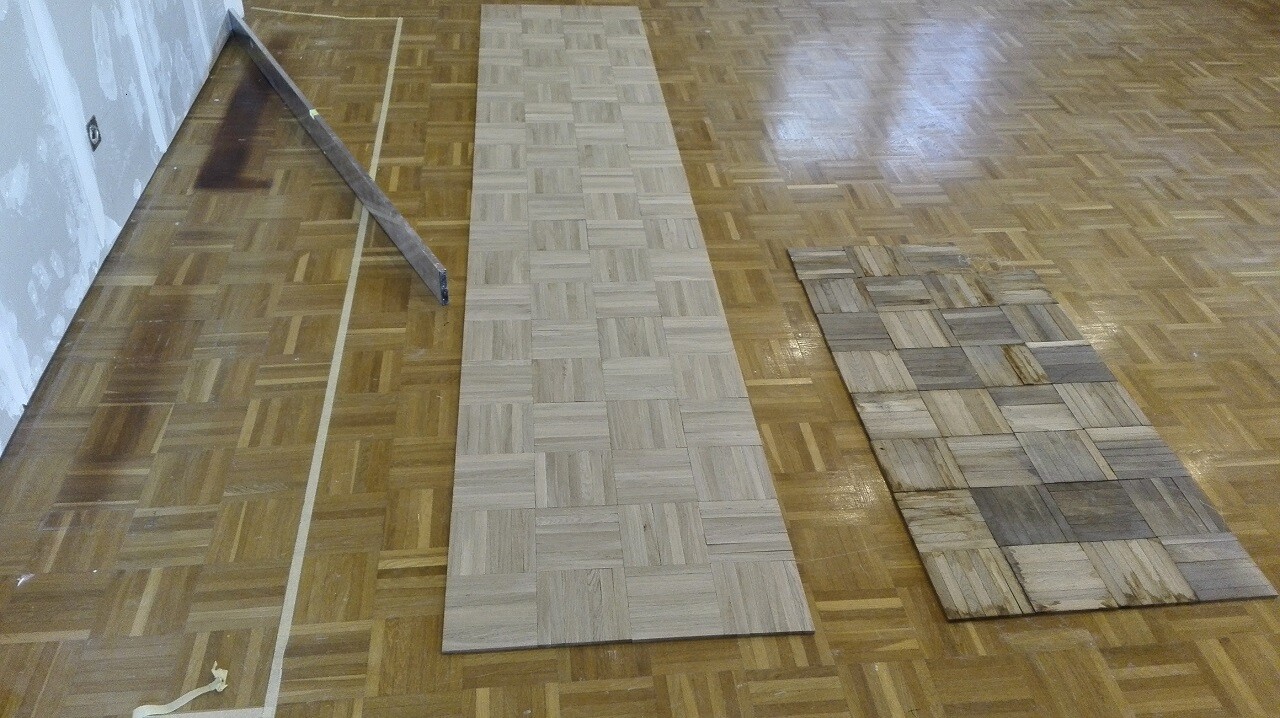 Parkett- und Mosaikboden liegen auf einem Holzboden, Renovierungsarbeiten sichtbar.