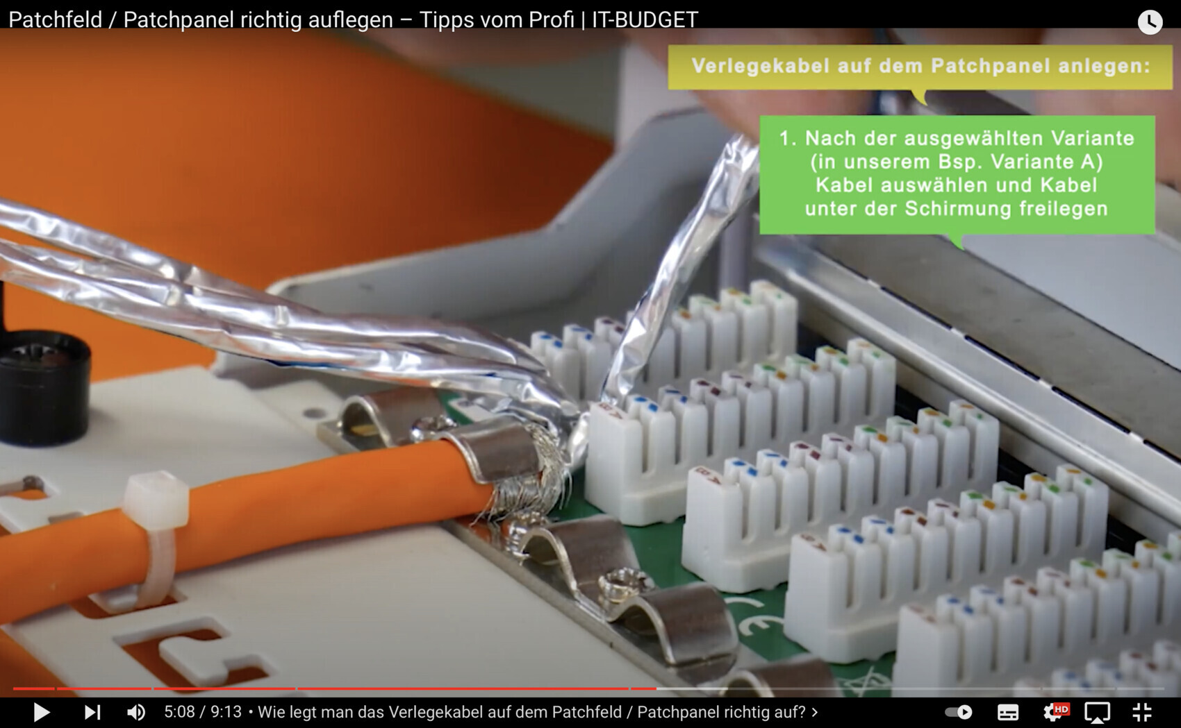 Nahaufnahme eines Patchpanels mit farbcodierten Steckplätzen und orange Kabel.