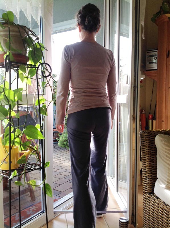 Rückansicht einer Person im Eingangsbereich vor offener Glastür zum Garten