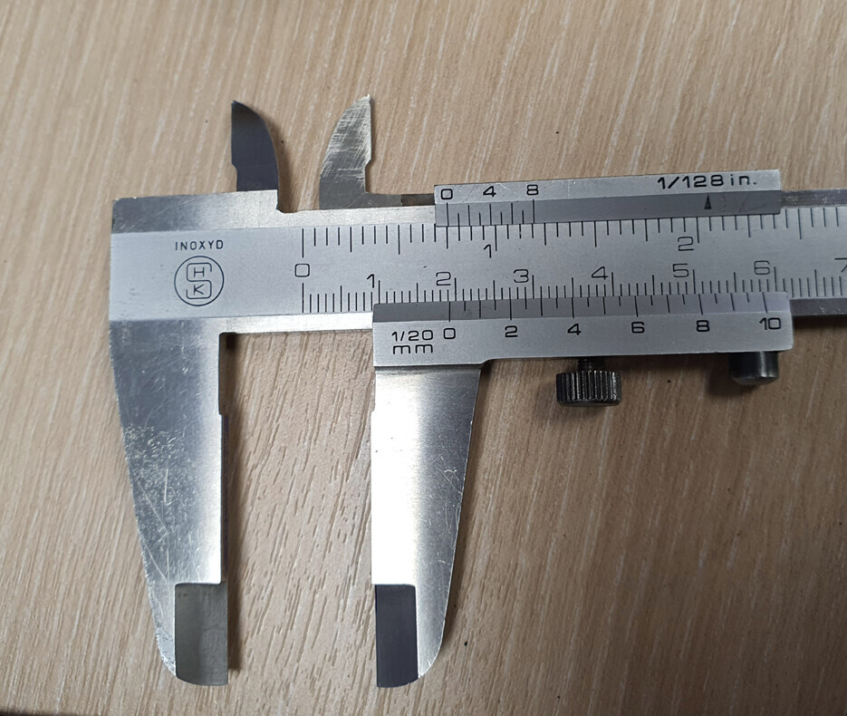 Metallischer Messschieber (Schieblehre) auf Holztisch, Skala gut lesbar.