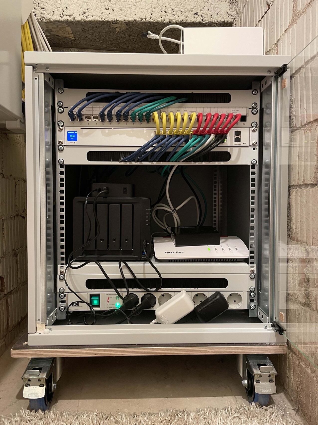 Netzwerkschrank mit Patchpanels, bunten Kabeln und Router im Metallrack.