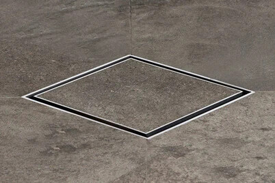 Quadratischer Metallrahmen als eingelassene Bodenöffnung im Betonboden.