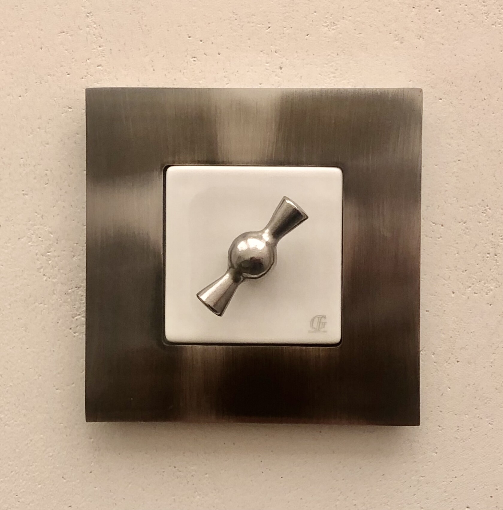 Quadratischer Wandlichtschalter aus Edelstahl mit weißem Innenrahmen.