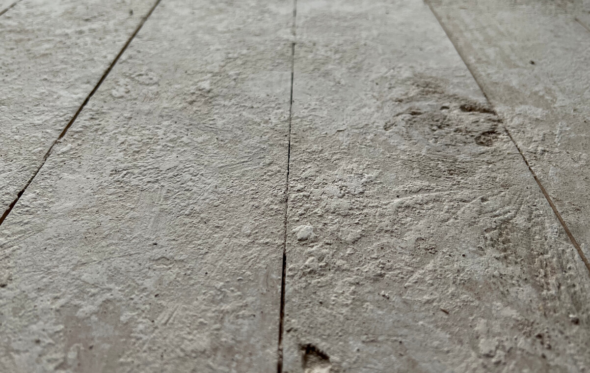 Nahaufnahme einer rauen, staubigen Bodenfläche aus Stein/Beton mit Fugen.