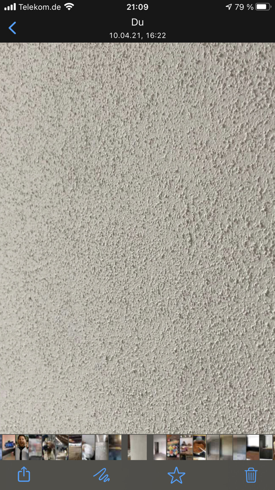 Nahaufnahme einer rauen, hellgrauen Putzwand mit unregelmäßiger Struktur.