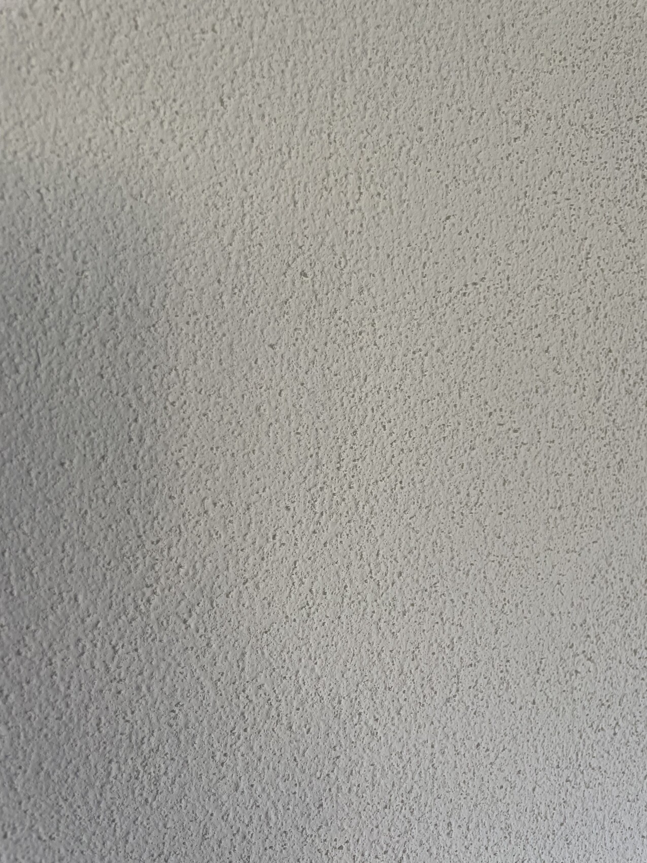 Nahaufnahme einer grauen, rauen Putzwand mit unregelmäßiger Oberfläche