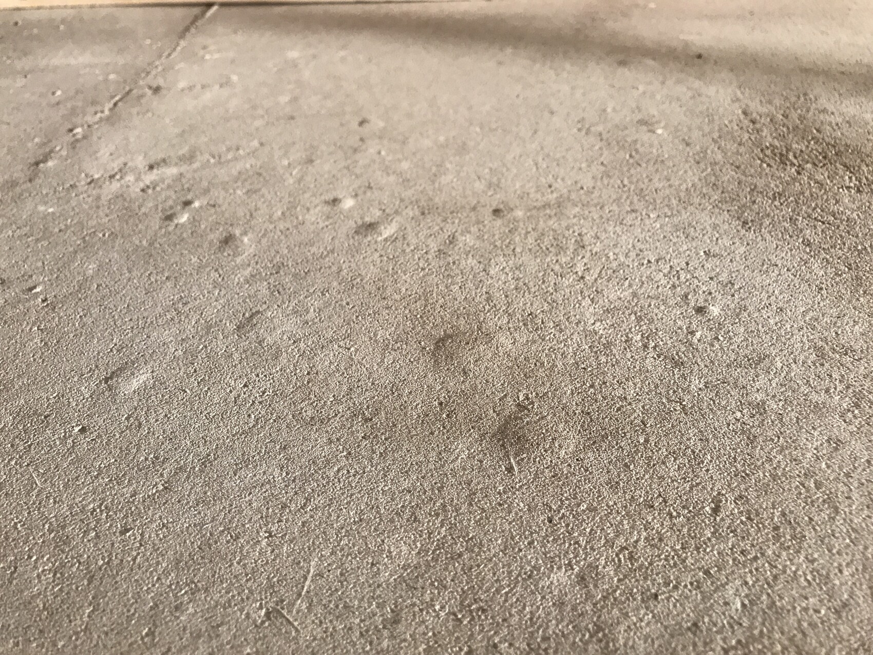 Nahaufnahme einer sandigen Bodenoberfläche mit feinem Staub und kleinen Eindrücken.
