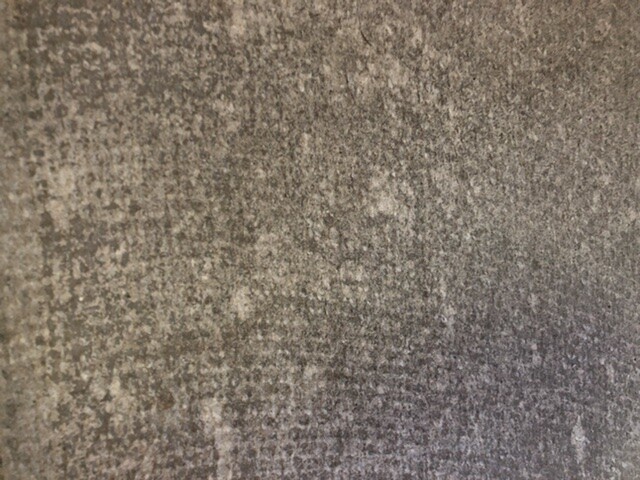 Nahaufnahme einer grauen, gesprenkelten Beton- oder Steinoberfläche mit weißen Flecken.