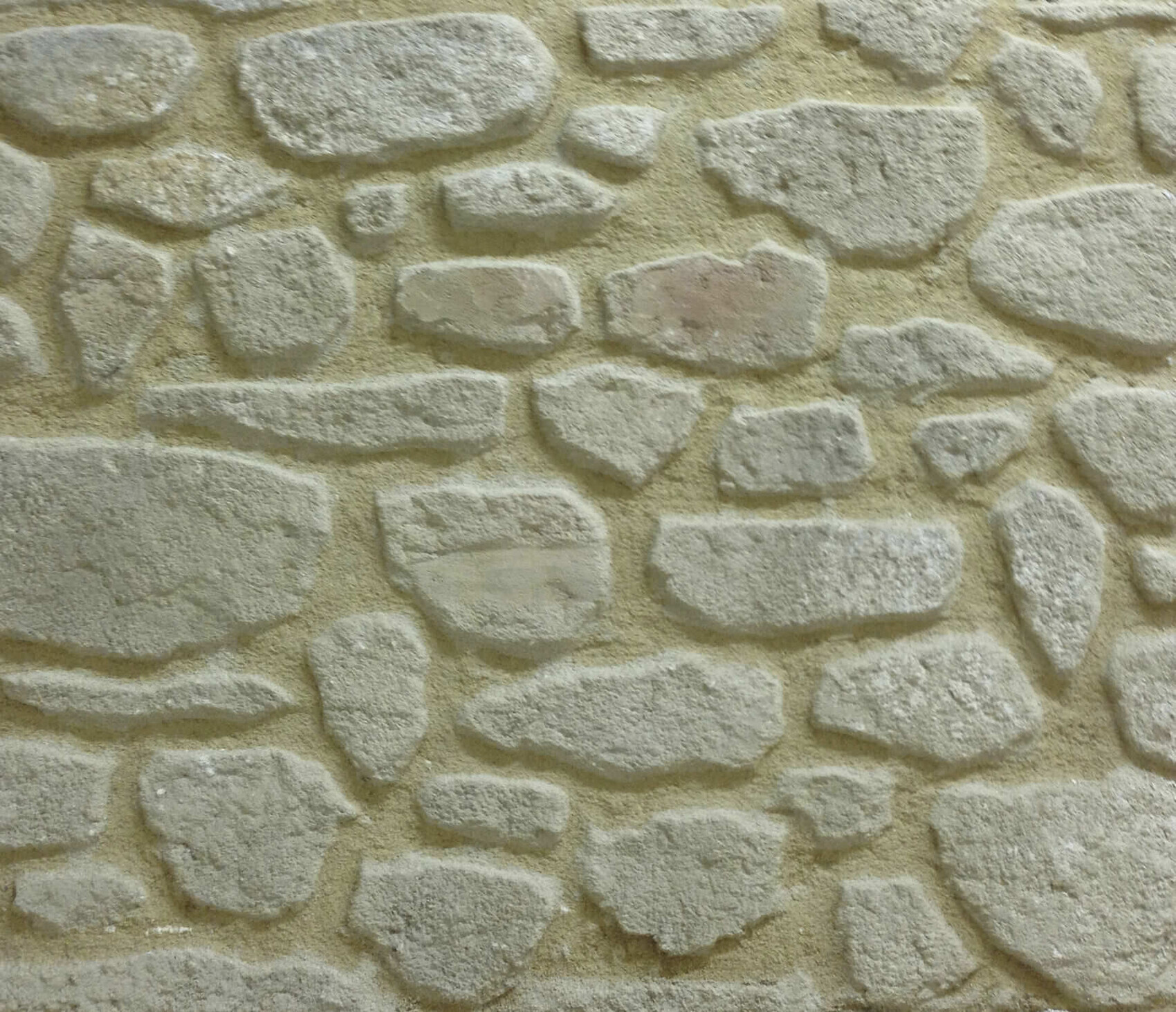 Steinmauer aus unregelmäßigen grauen Steinen mit sandigem Mörtel