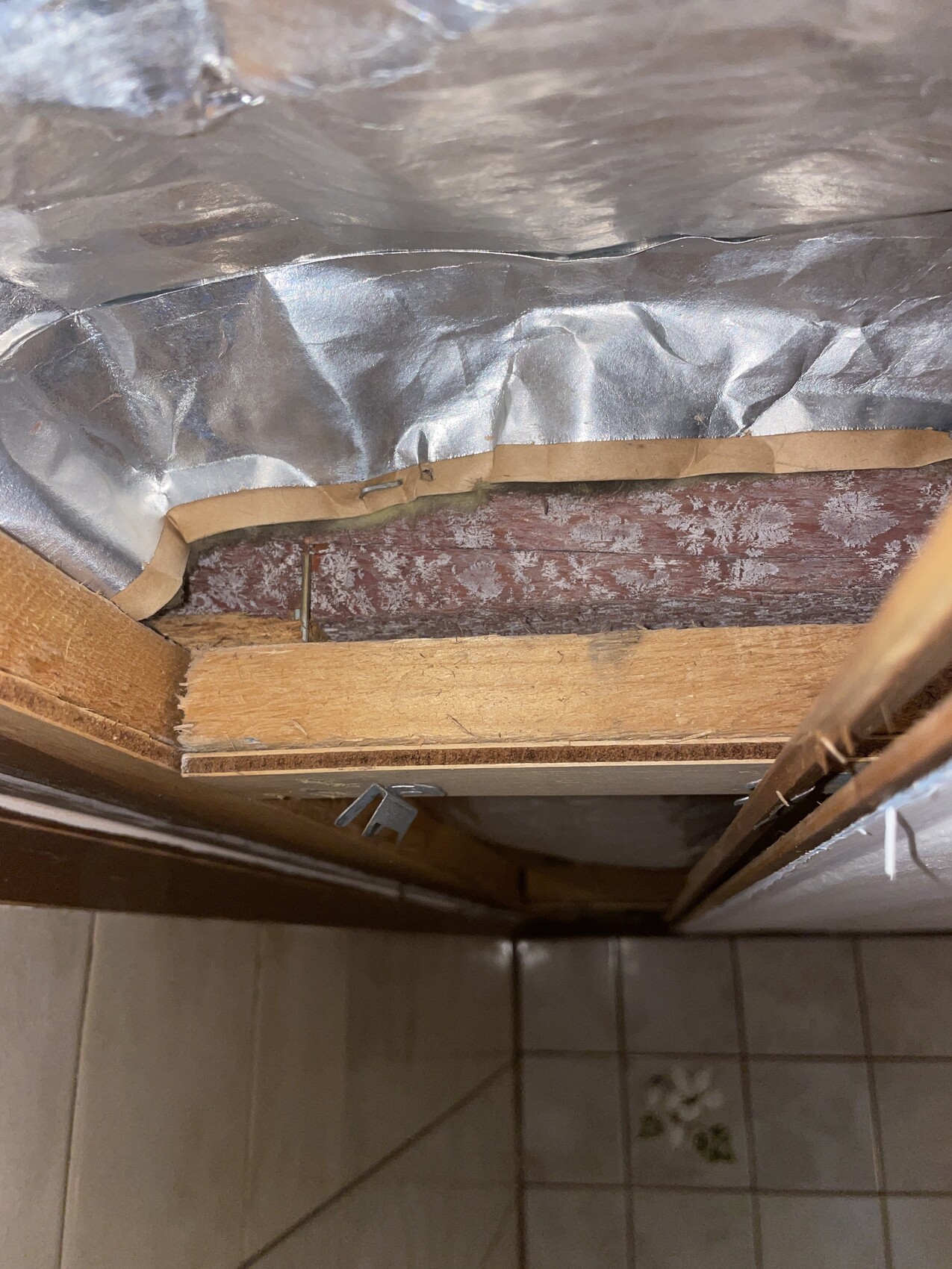 Deckenhohlraum mit Aluminiumfolie-Isolierung, sichtbaren Holzbalken und offenem Raum.