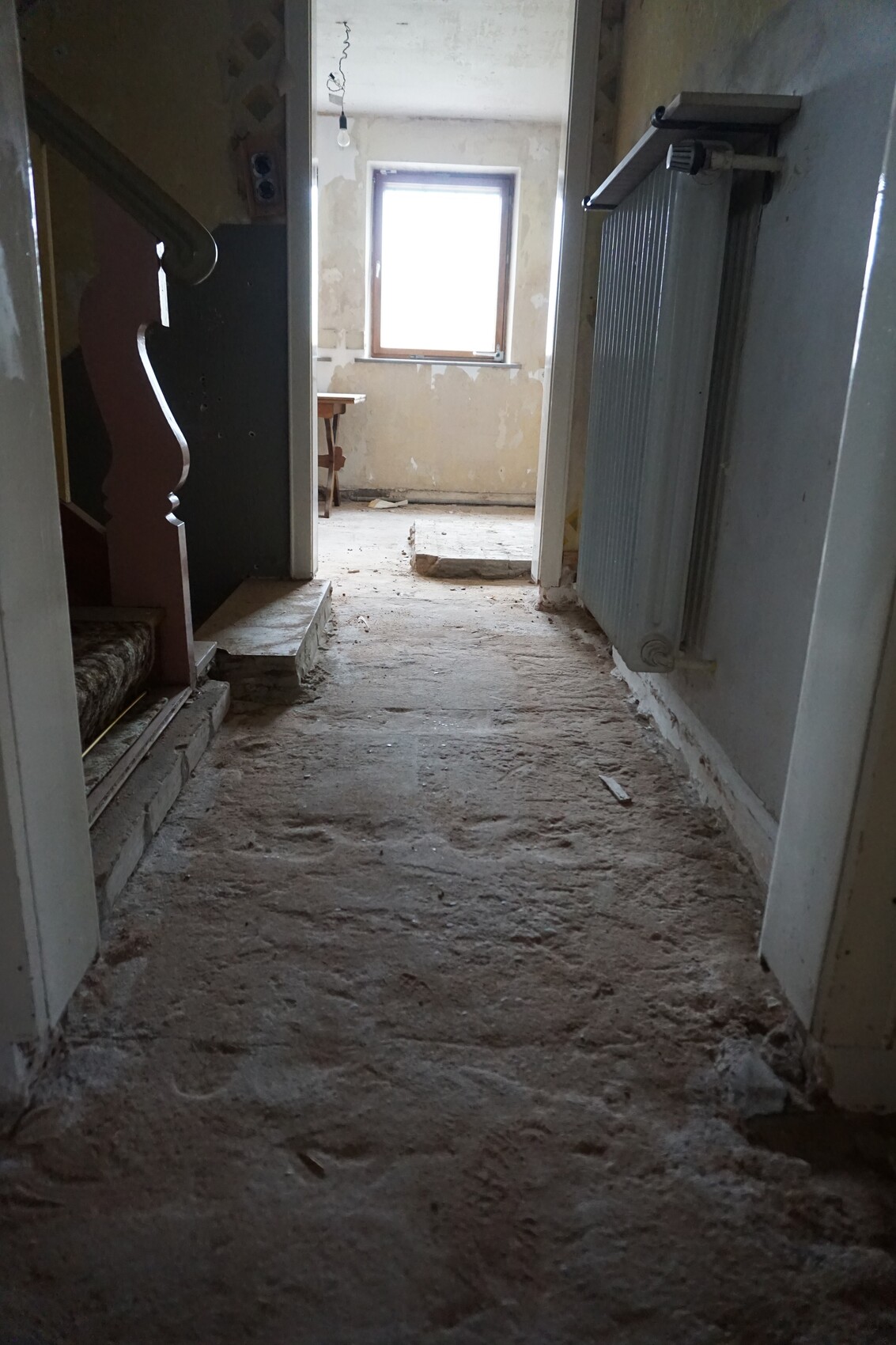 Verlassener Flur eines renovierungsbedürftigen Hauses, staubig, Fenster am Ende.