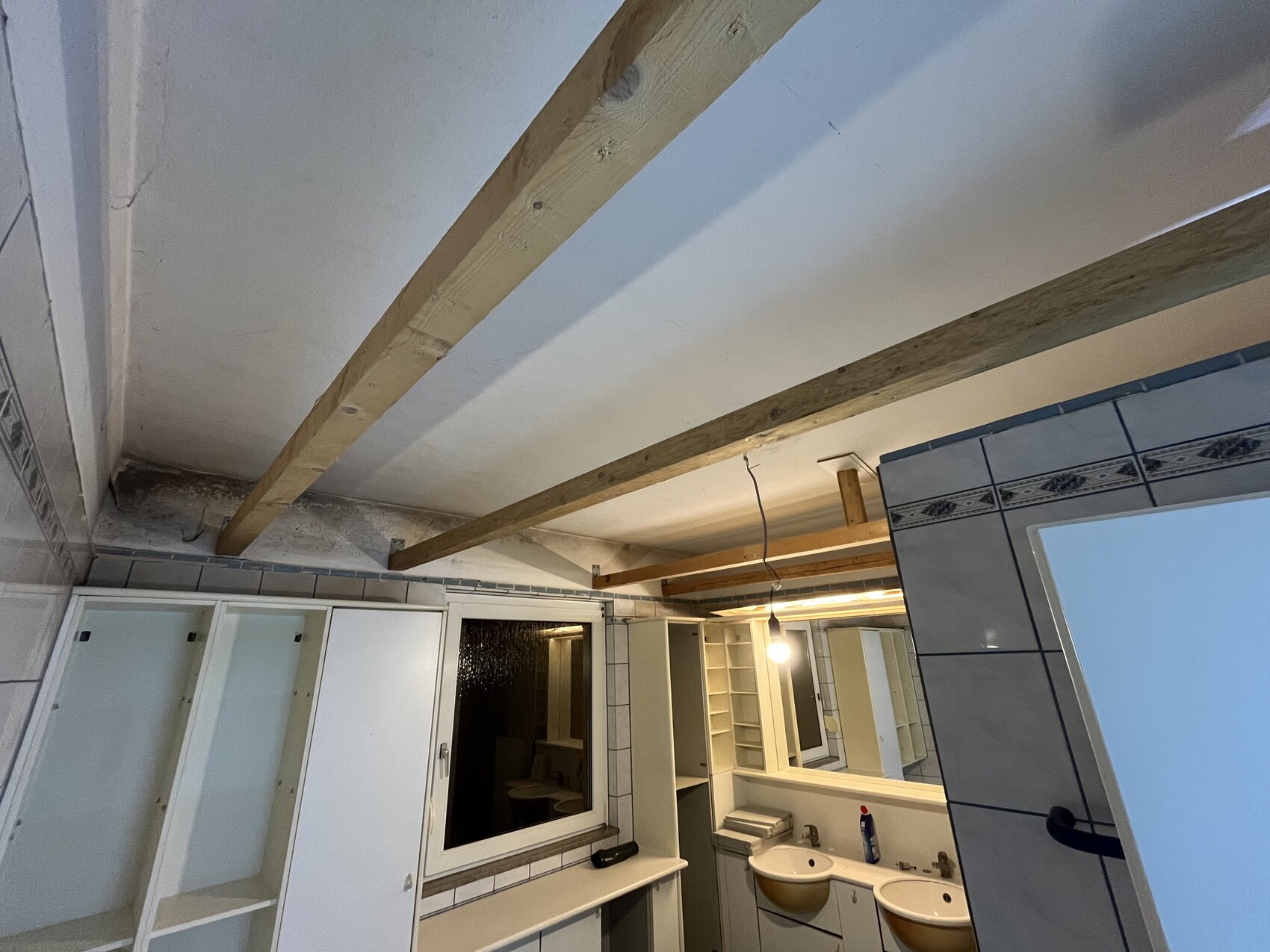 Badezimmer unter Renovierung mit Holzbalken, Spiegel und Doppelwaschbecken