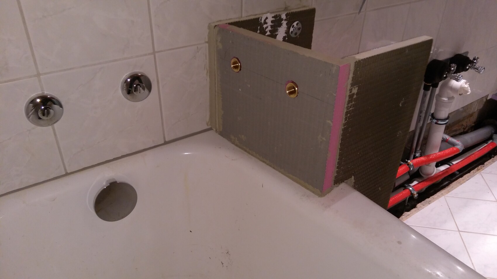 Badezimmer: Badewanne mit sichtbaren Rohren und Dämmplatte auf der Kante.