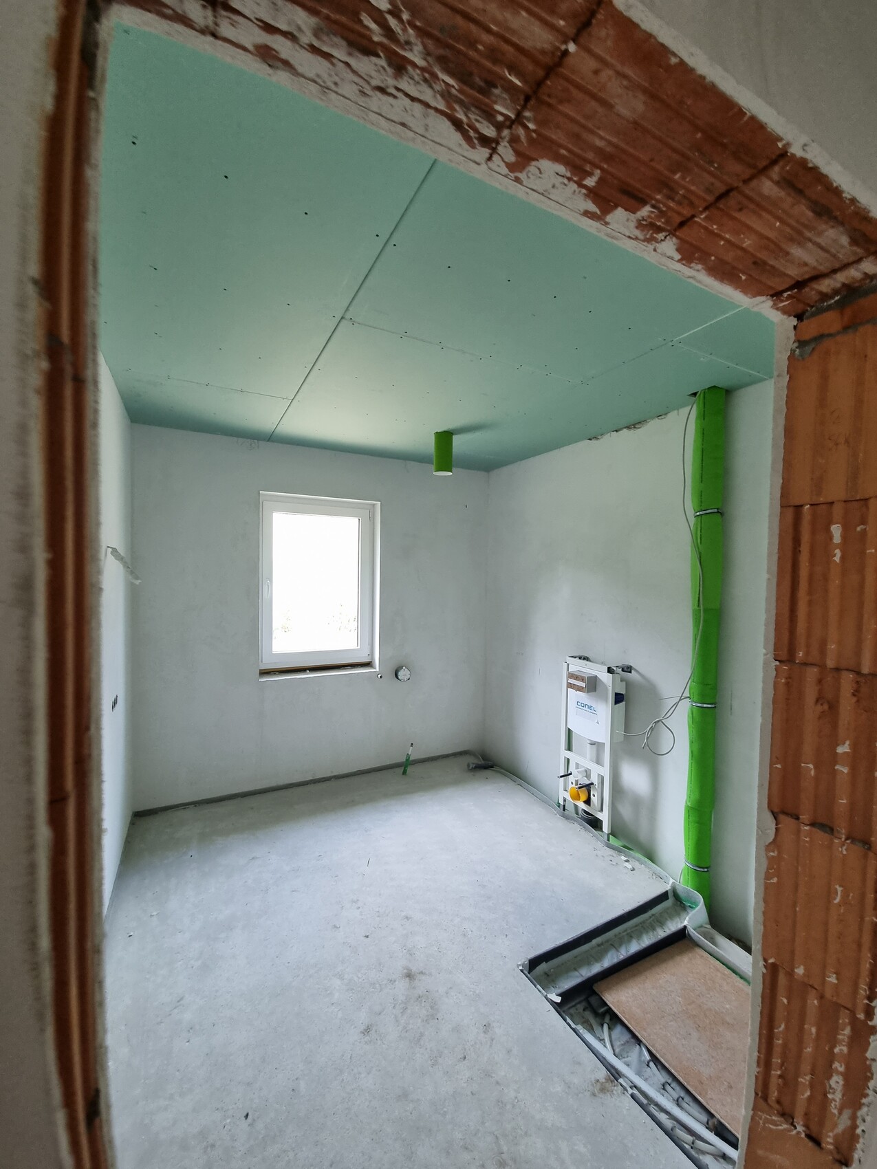 Renoviertes Bad im Unterbau mit Sanitärinstallationen und grünem Deckensegel