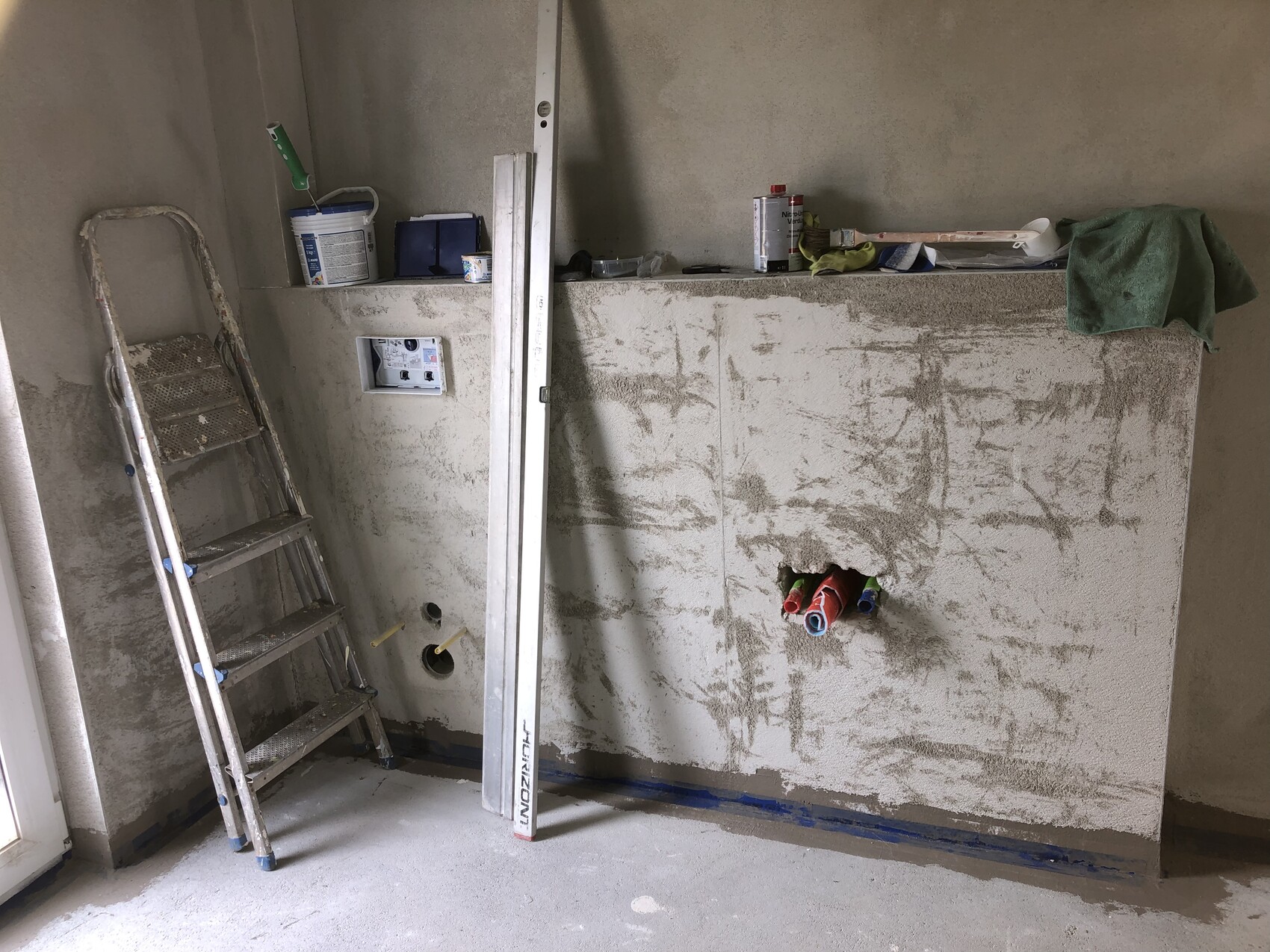 Renovierungsraum: Leiter vor Wand, Rohre ragen, Werkzeugkisten und Materialien liegen bereit.