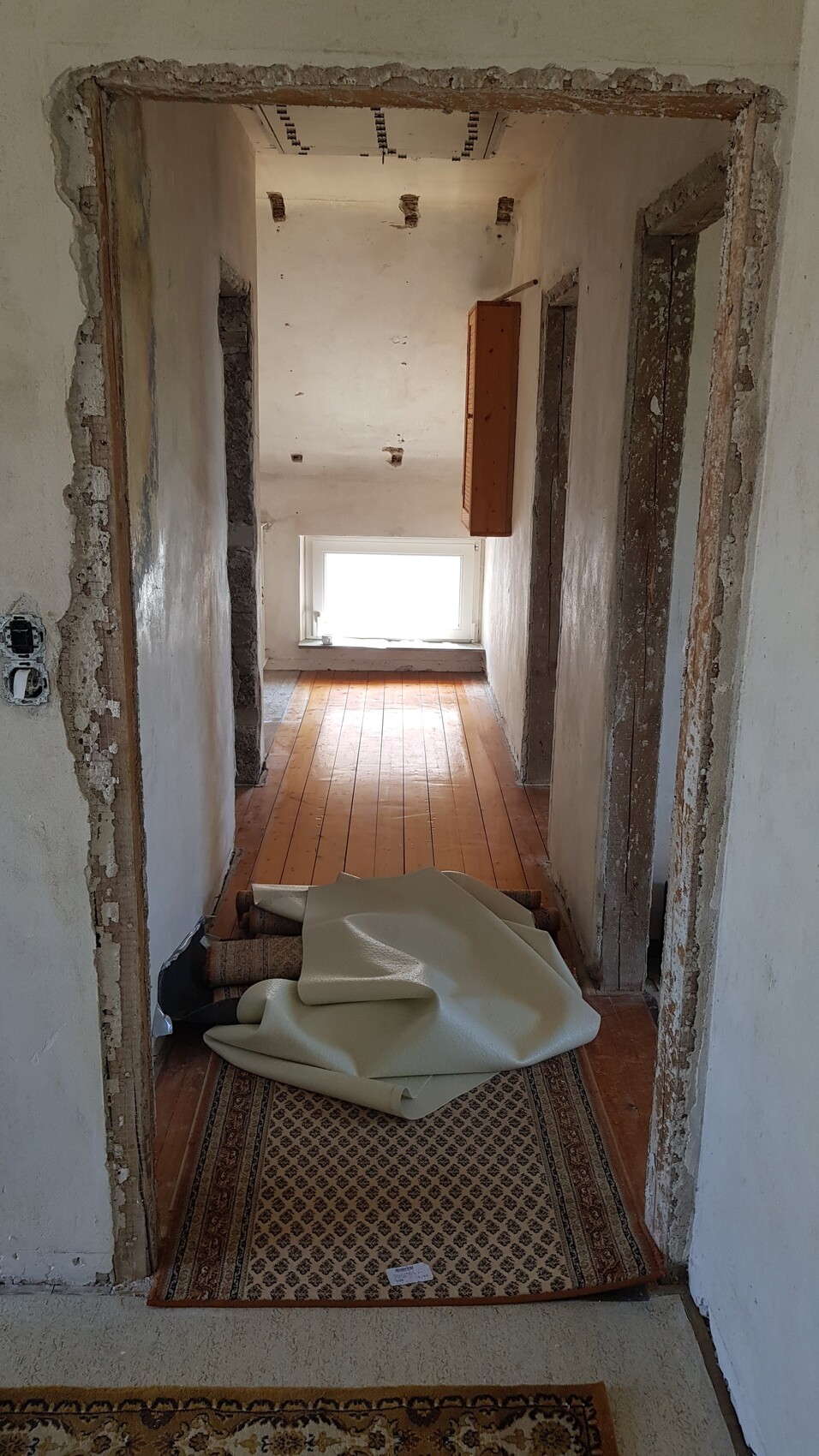 Flur im Rohbau einer Wohnung, Holzboden, offene Wände, Renovierungsarbeiten