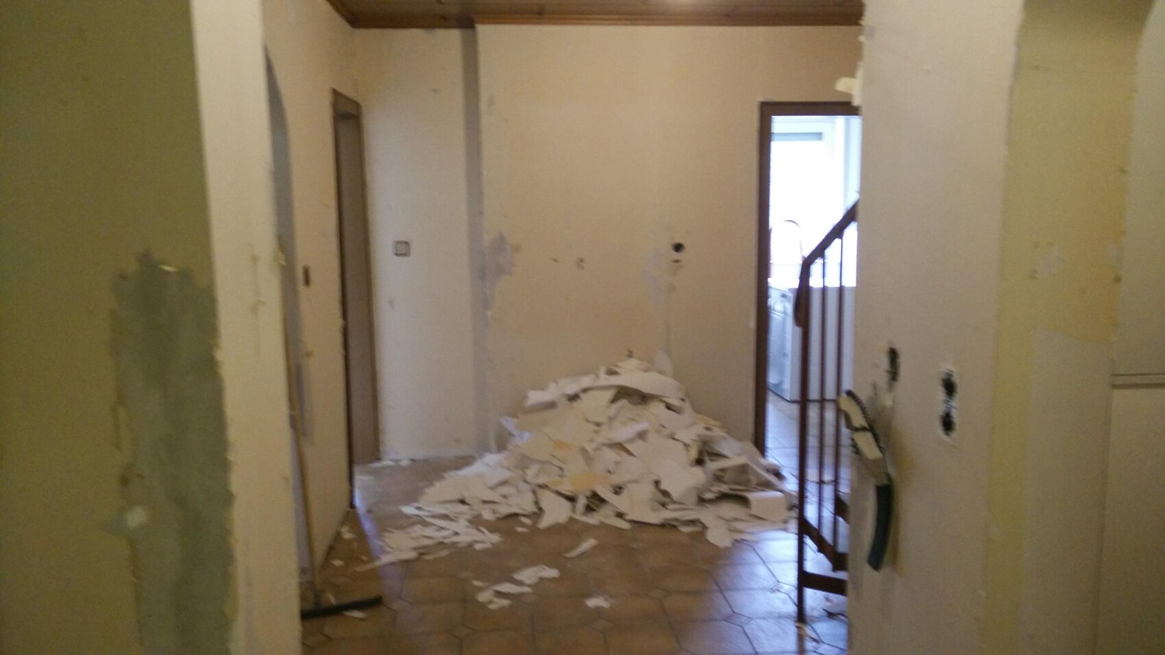 Flur während Renovierung mit Putz- und Papierrückständen auf dem Boden und Treppe im Hintergrund