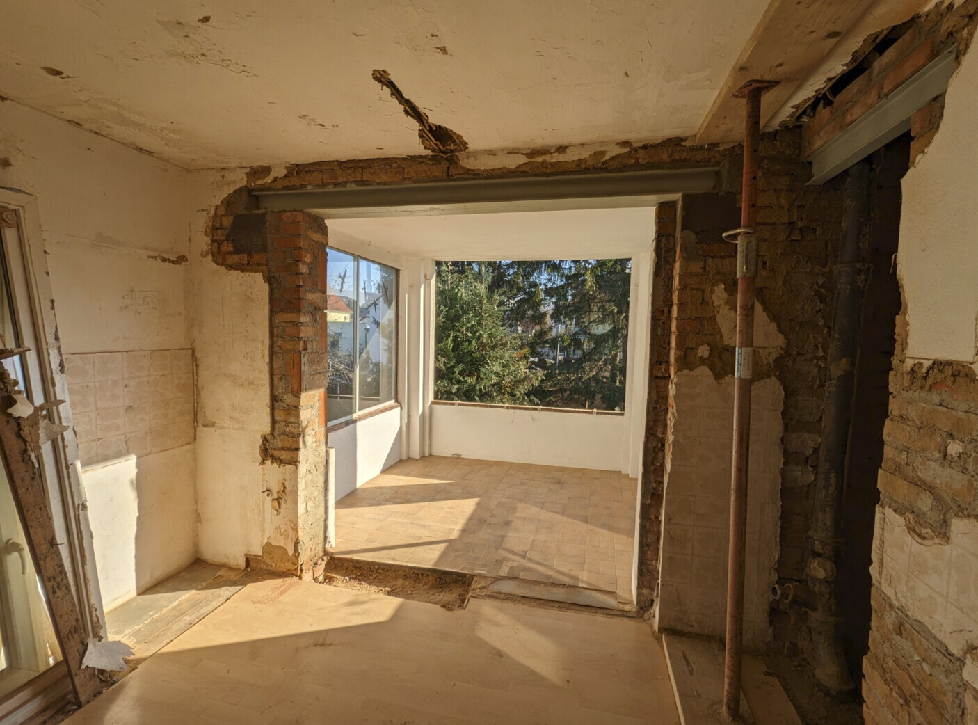 Renovierungsarbeiten: Innenraum mit offener Bruchsteinwand, Fensterfront zum Balkon
