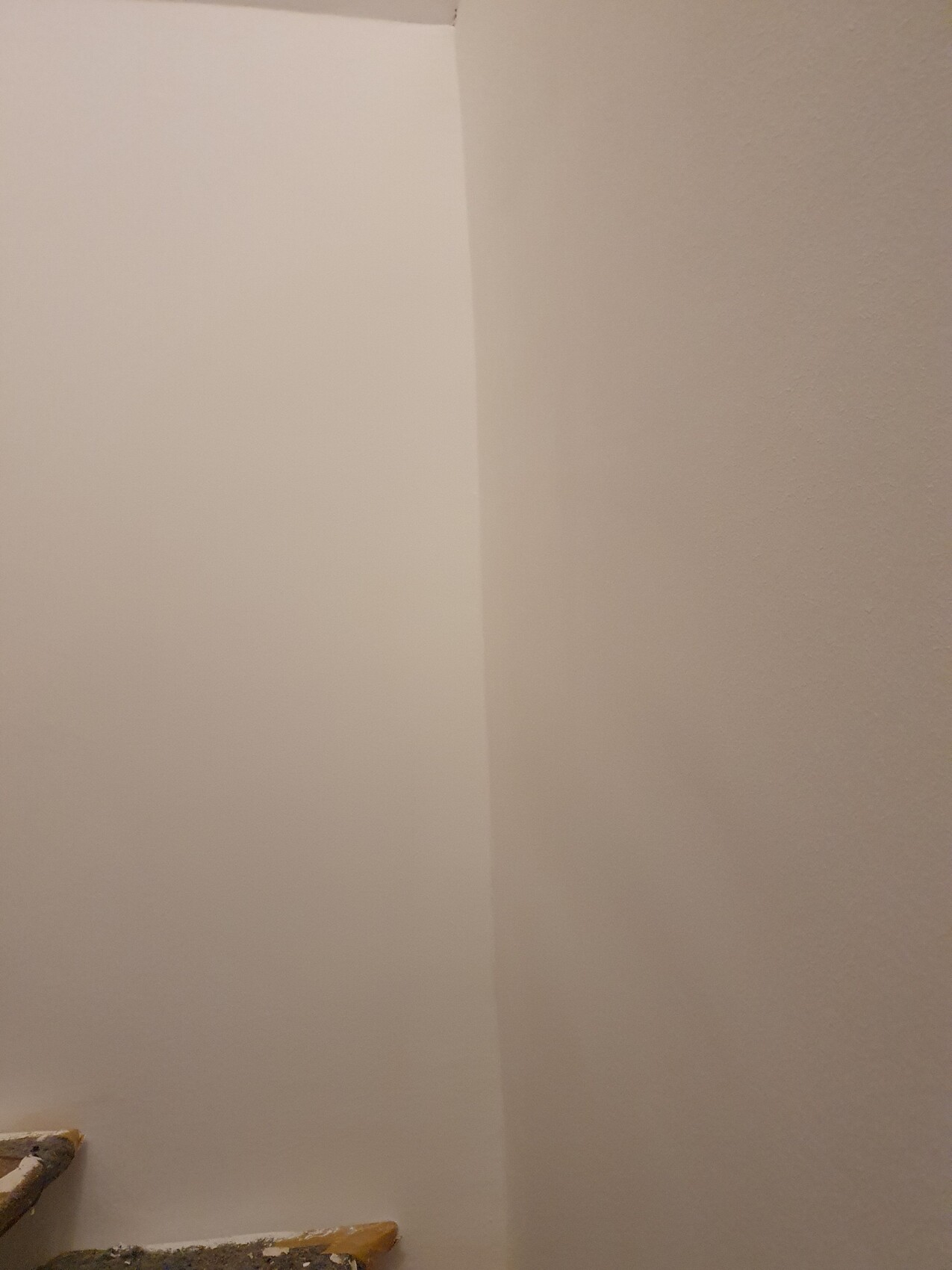 Helle Innenwandenecke mit Treppe am unteren Rand, Renovierungsarbeiten sichtbar