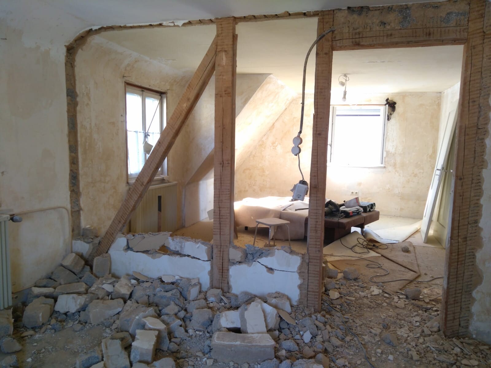 Innenraum unter Renovierung mit freigelegten Holzbalken, Schutt und Werkzeugen