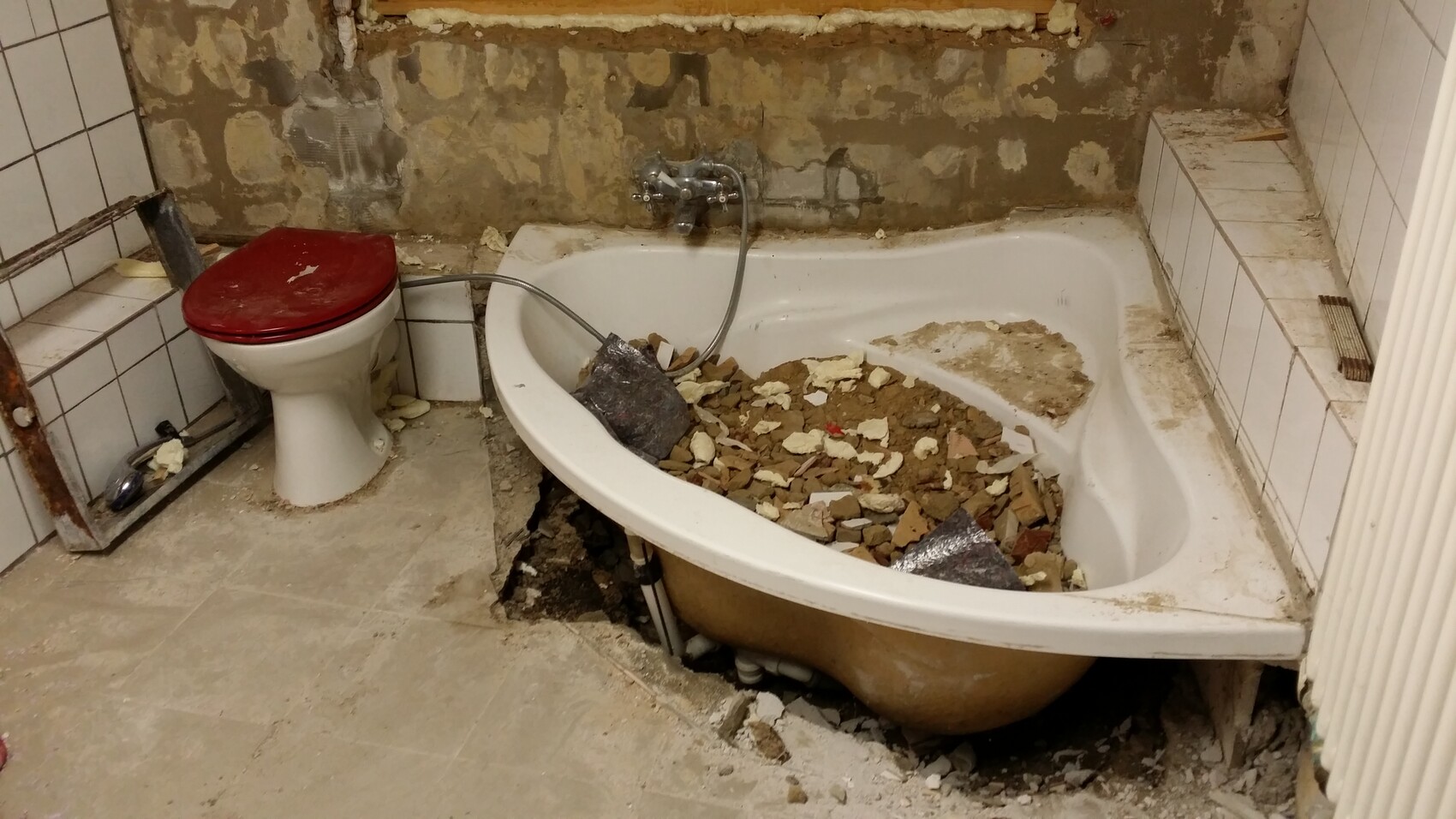 Badezimmer unter Renovierung mit freigelegter Badewanne und Mörtelresten