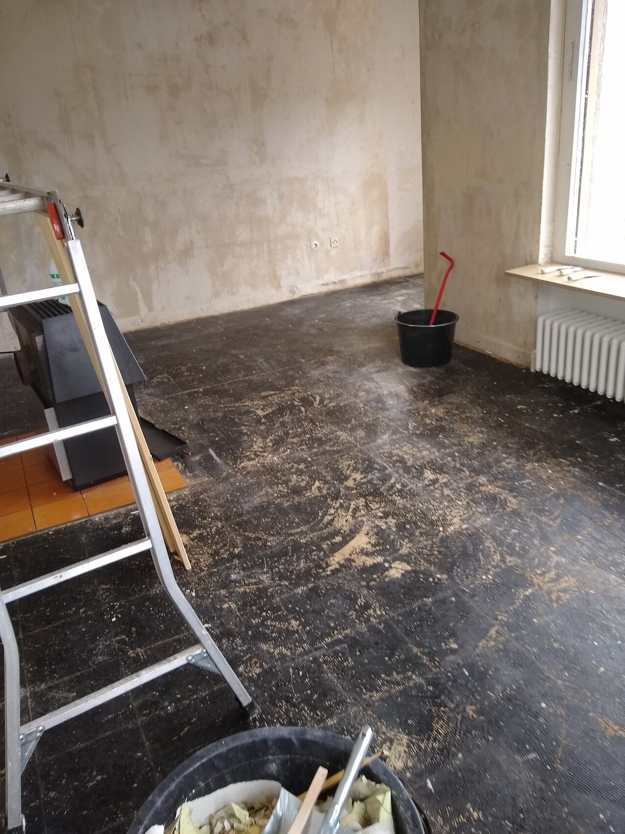 Innenausbau: Leiter, Eimer und Baumaterial in einem renovierungsbedürftigen Raum