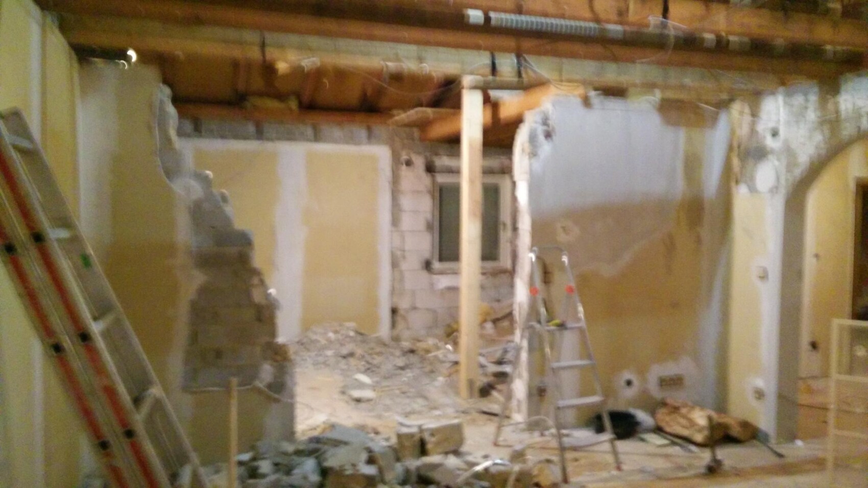 Innenraum-Baustelle mit freigelegten Wänden, Leitern und Schutt