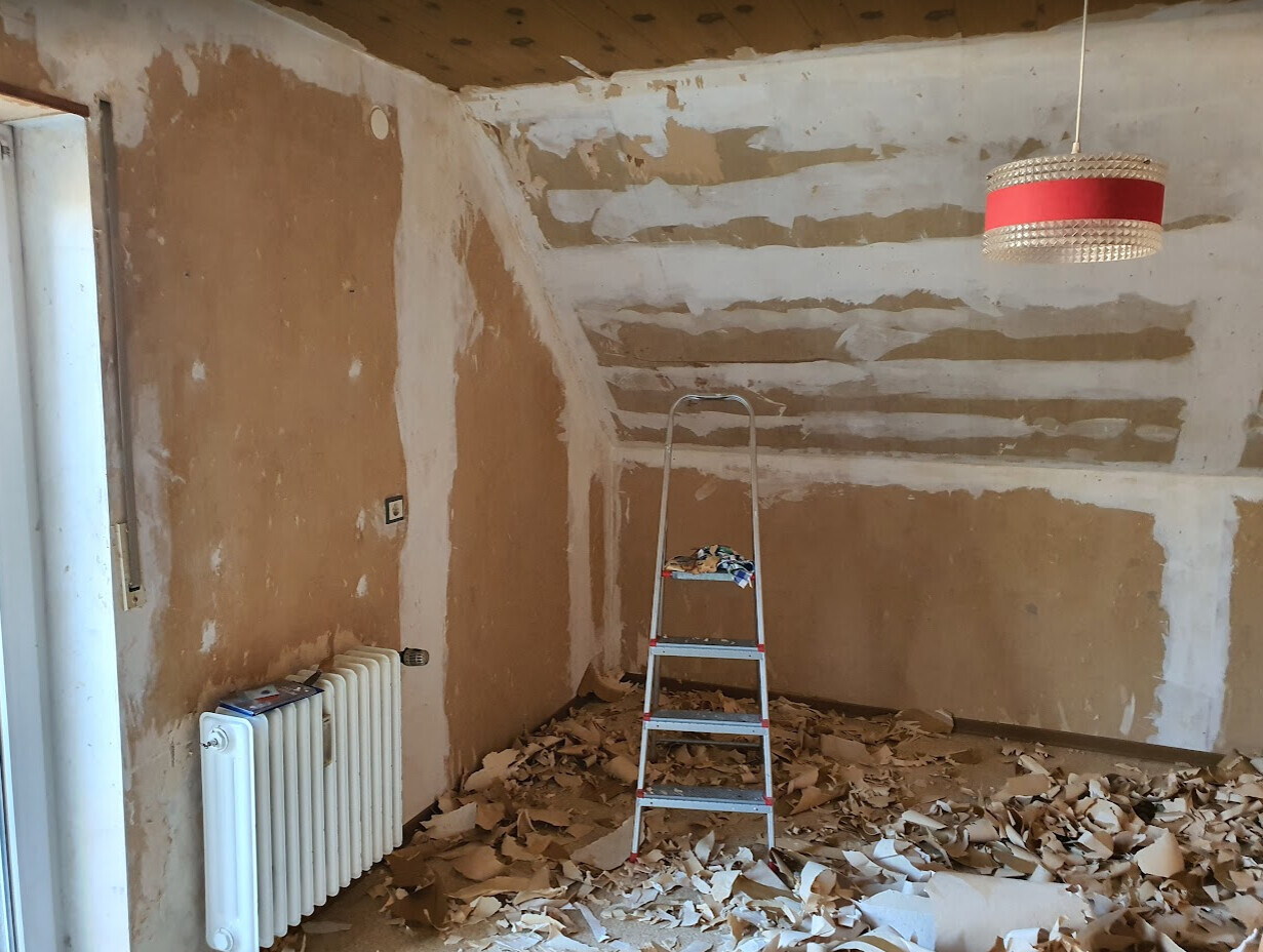 Renovierungsraum: Leiter in der Mitte, Putzreste auf dem Boden, roter Lampenschirm.