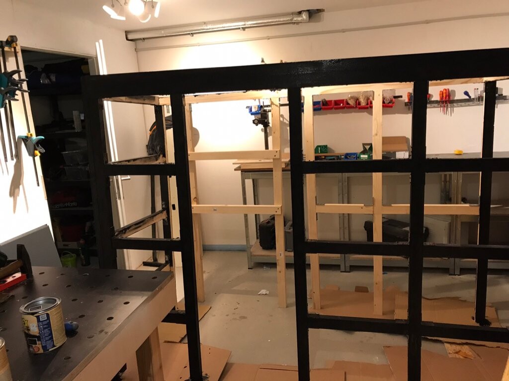 Große schwarze Metallrahmenkonstruktion mit Holzbalken in der Werkstatt.