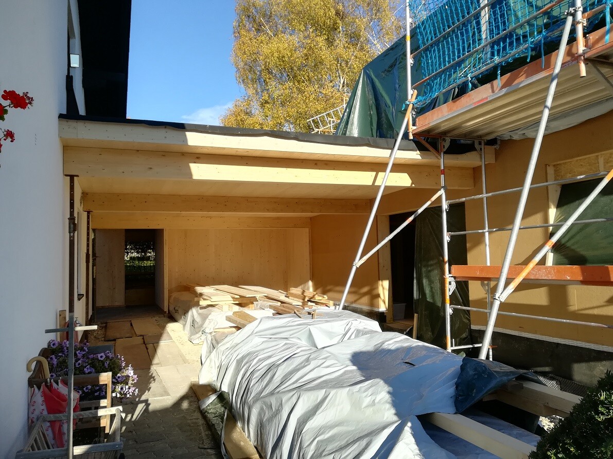 Baustelle am Haus mit Holzbalken, Gerüst und gestapelten Bauteilen