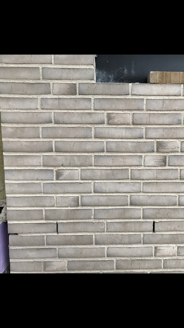 Außenwand aus grauen Ziegelsteinen im Rohbau, unvollständige Mauerstruktur