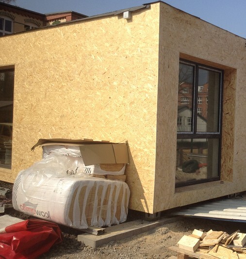 Außenansicht eines Rohbaus mit OSB-Verkleidung und großem Fenster