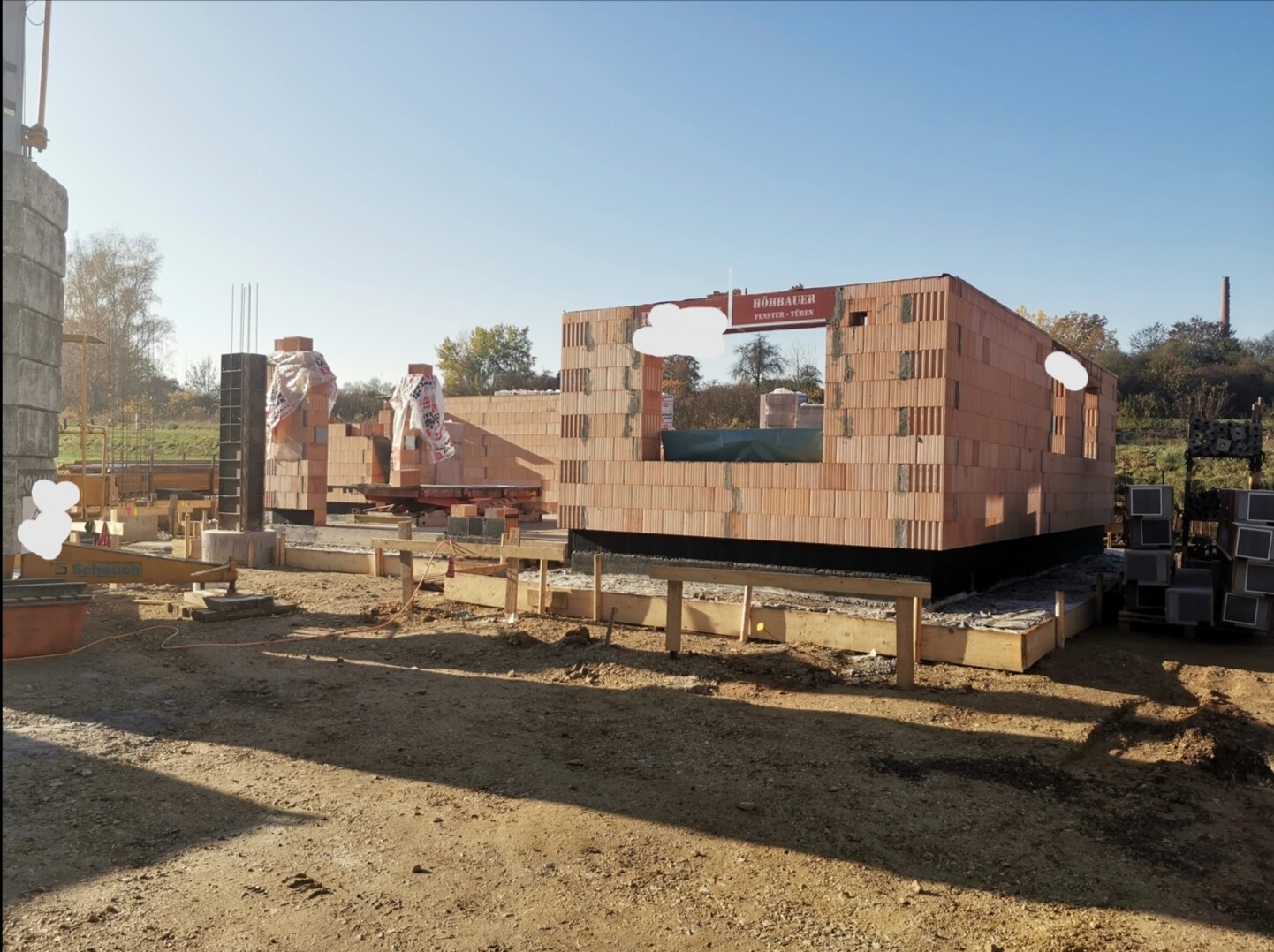 Unfertiges Gebäude aus Ziegelsteinen auf Baustelle mit Fenster- und Türöffnung, Baumaterialien.