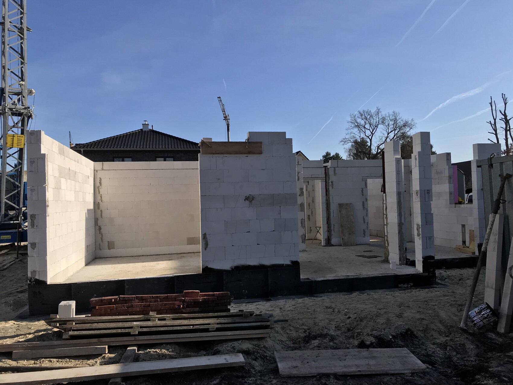 Baustelle mit weissen Betonwaenden aus Bloecken, Kraene im Hintergrund
