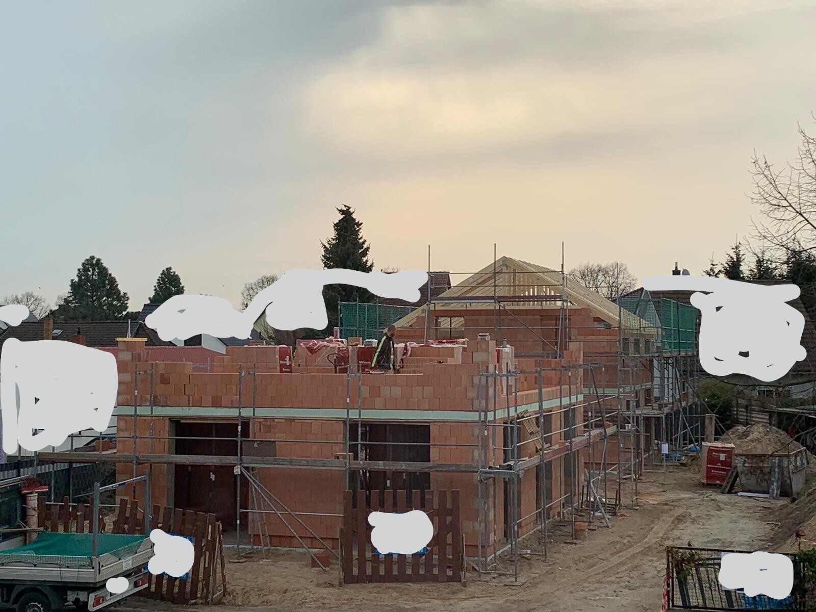 Rohbau aus roten Ziegeln mit Gerüst und Bauarbeiten auf einer Baustelle.