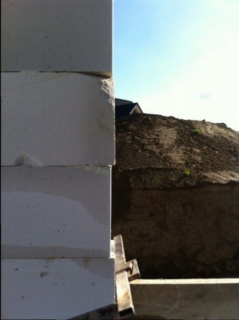 Baustelle mit Betonblockwand links und Erdhügel rechts, Bauwerk im Entstehen